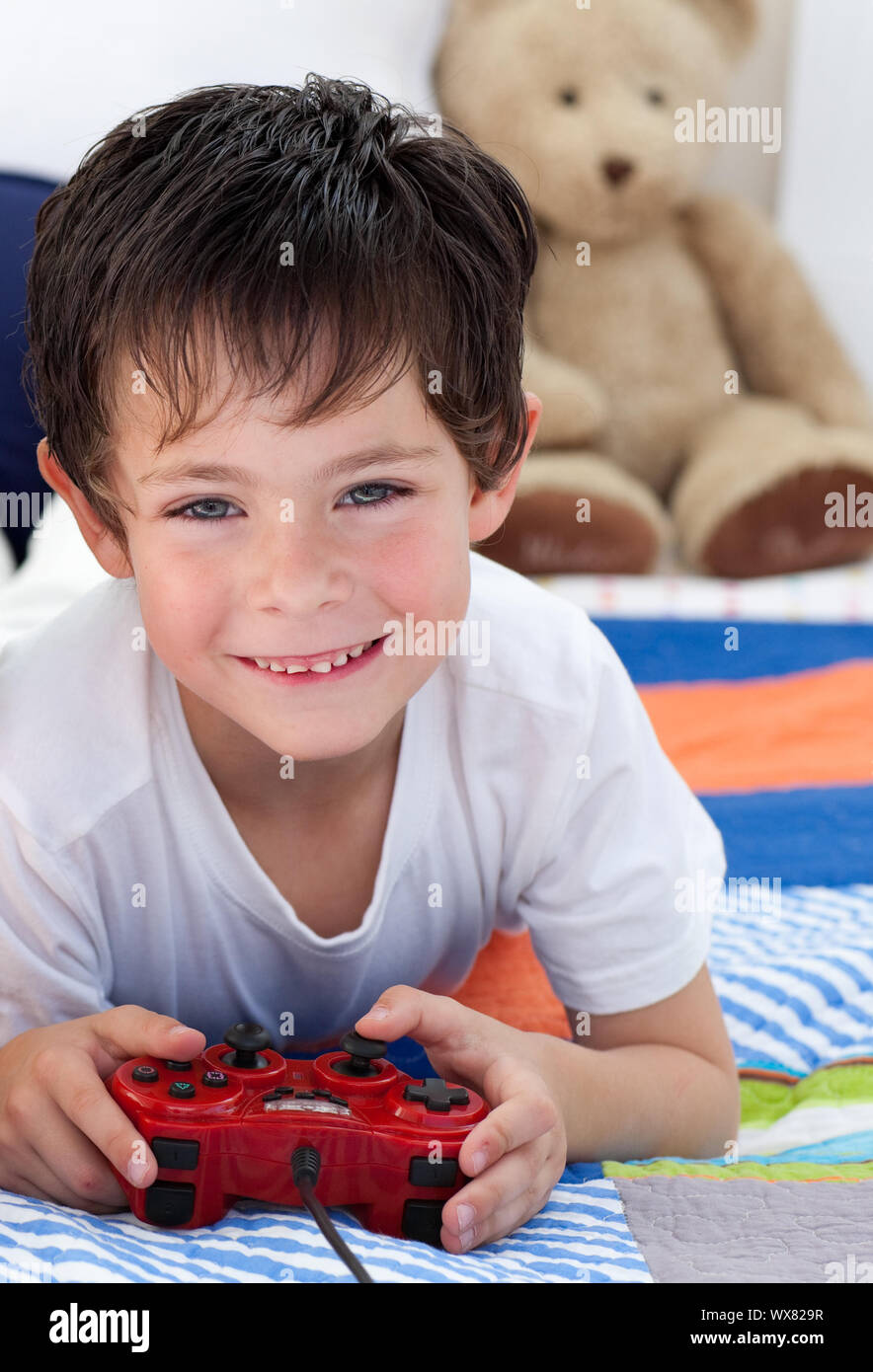Little boy playing video games and lying on bed Stock Photo - Alamy