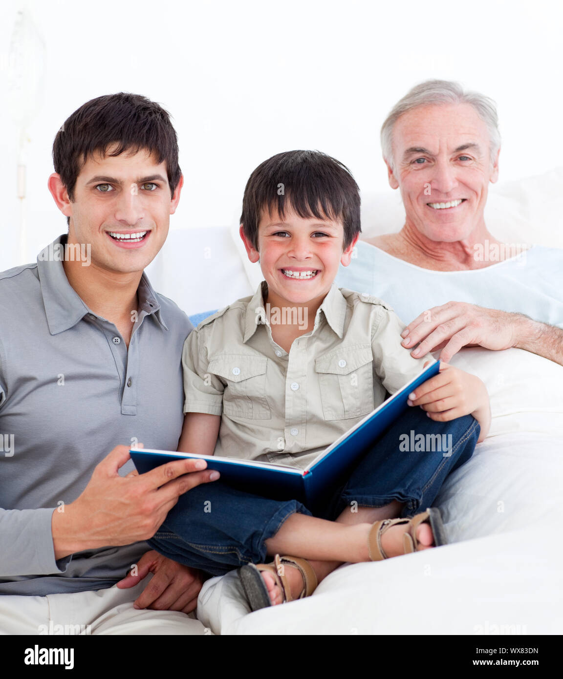 Laughing father and son visiting grandfather at the hospital Stock Photo