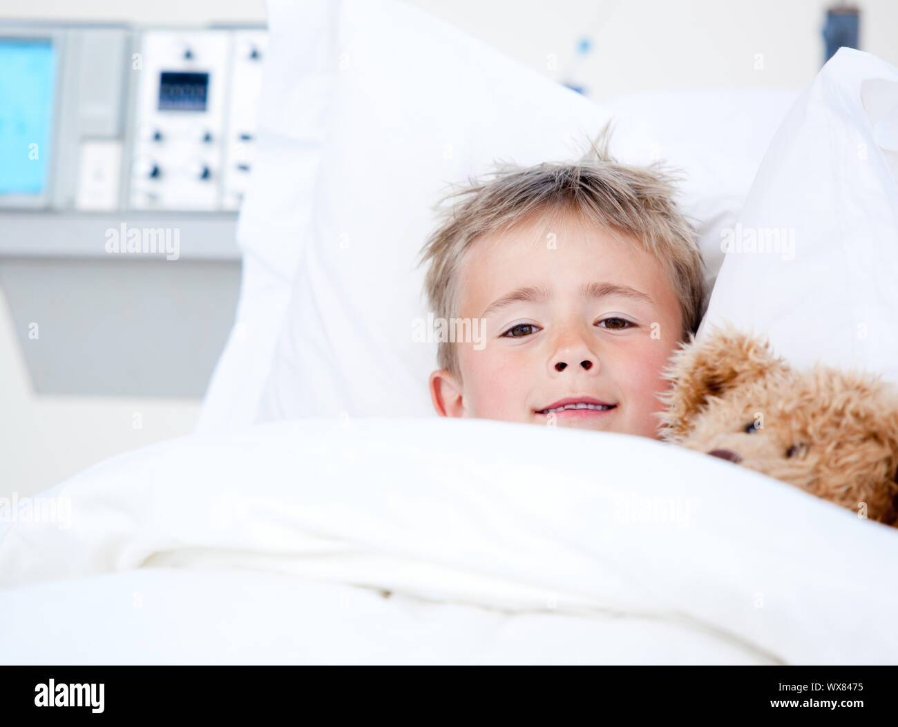 Portrait of a sick adorable little boy lying in a hospital bed with his