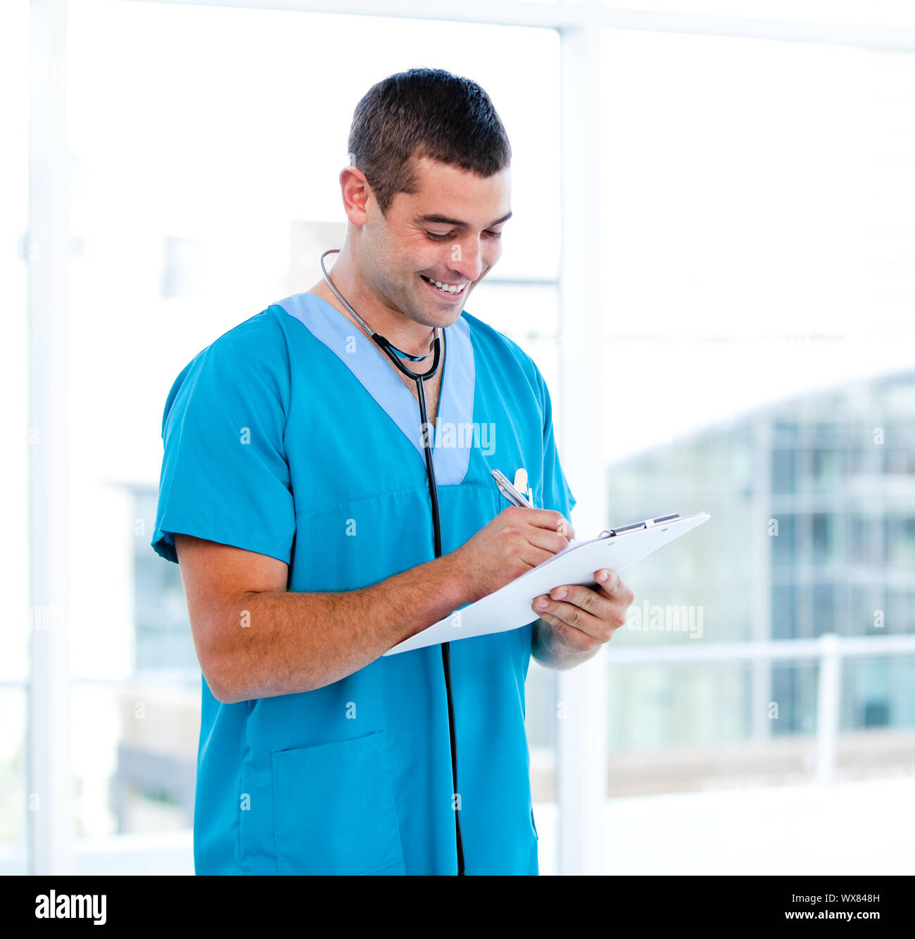 Concentrated male doctor making notes in a patient's folder in a ...