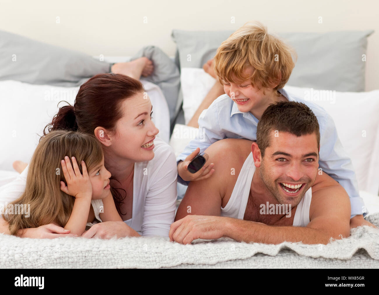 Family lying in bed watching television and son using a remote Stock Photo