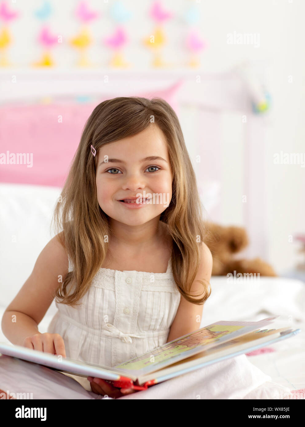 Little girl reading a book sitting in bed Stock Photo - Alamy