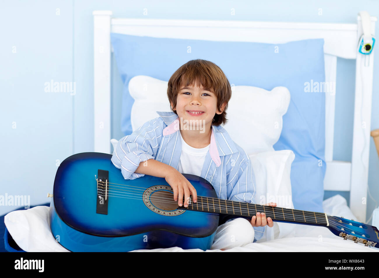 Happy Little Boy Playing Guitar Sitting In Bed Stock Photo Alamy