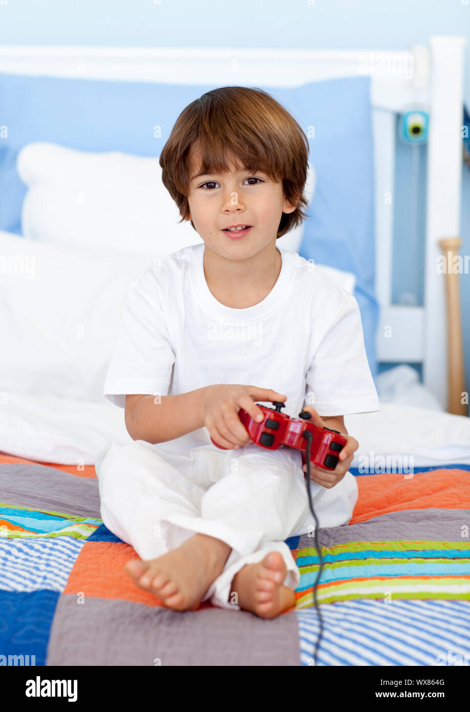 Little boy sitting in bed playing videogames Stock Photo Alamy