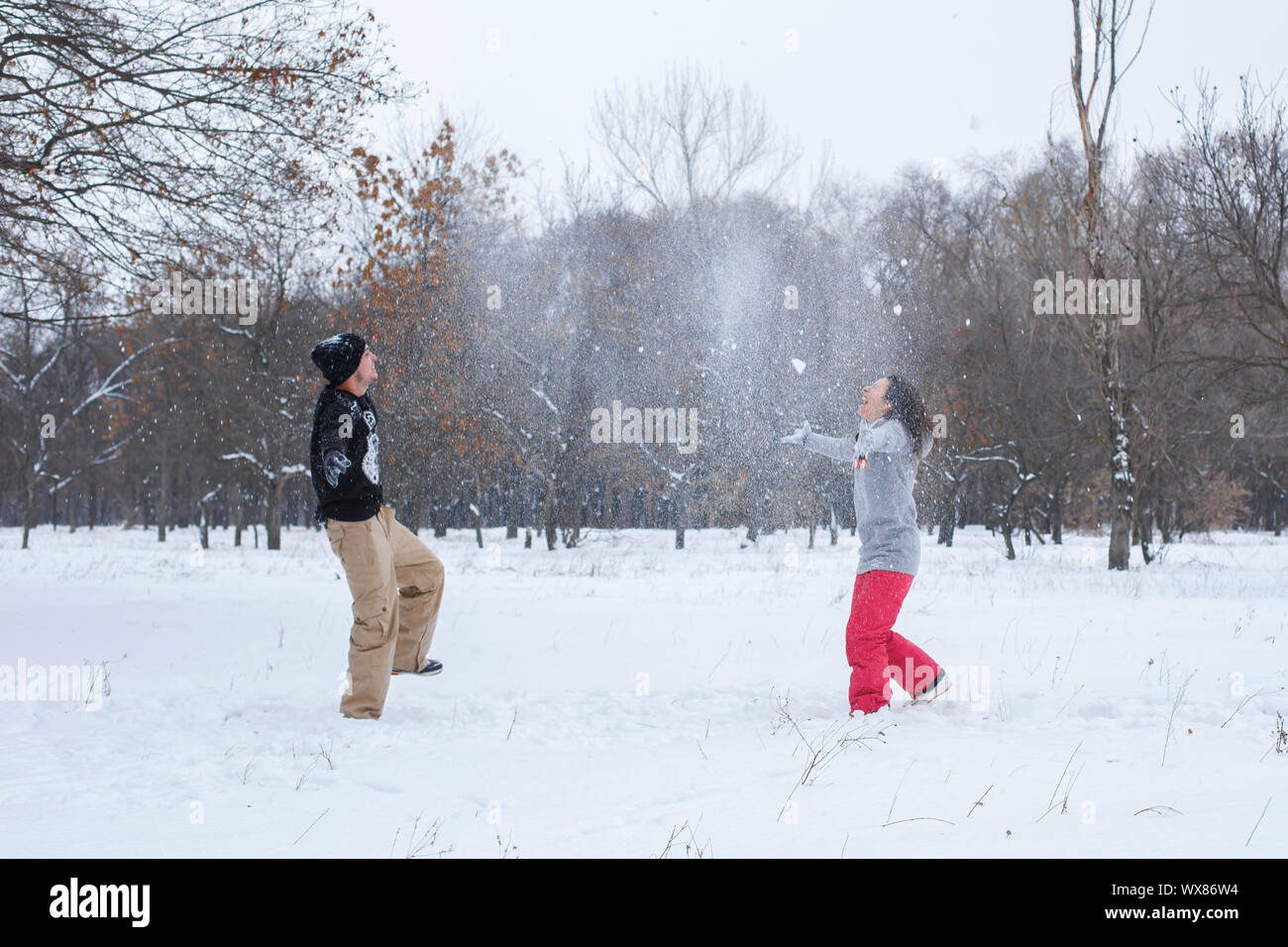 Loving couple having fun, laughing, playing and throwing snowballs in a ...