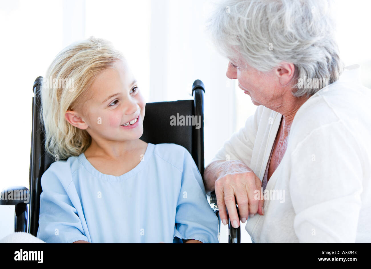 Cute little girl sitting on a wheelchair talking with her grandmother in a hospital Stock Photo