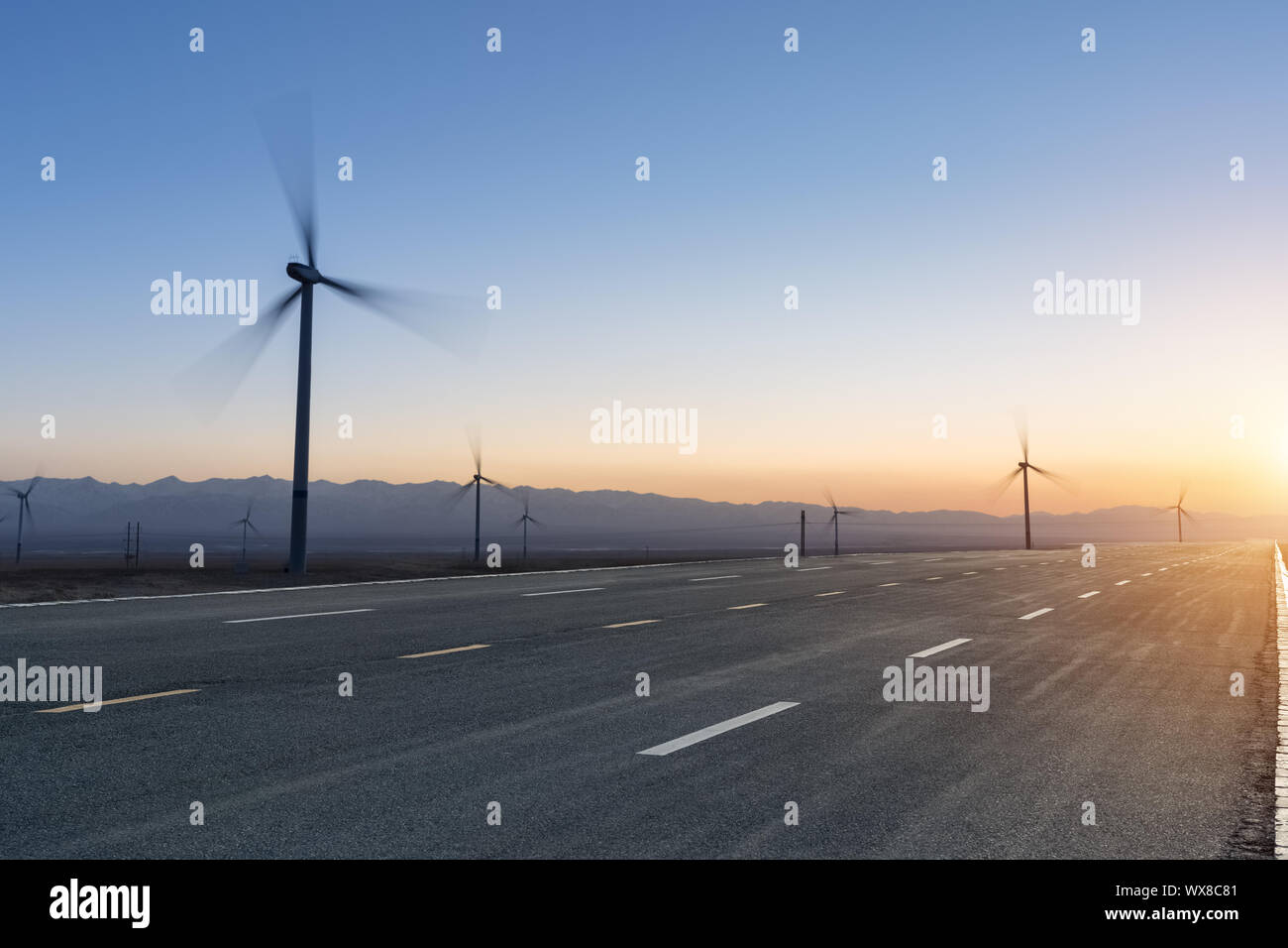 road and wind farm at dusk Stock Photo