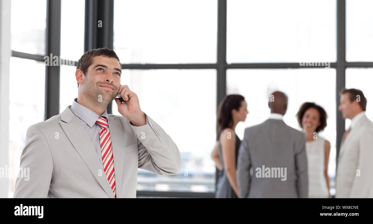 Enthousiastic businessman on phone in office with his team Stock Photo