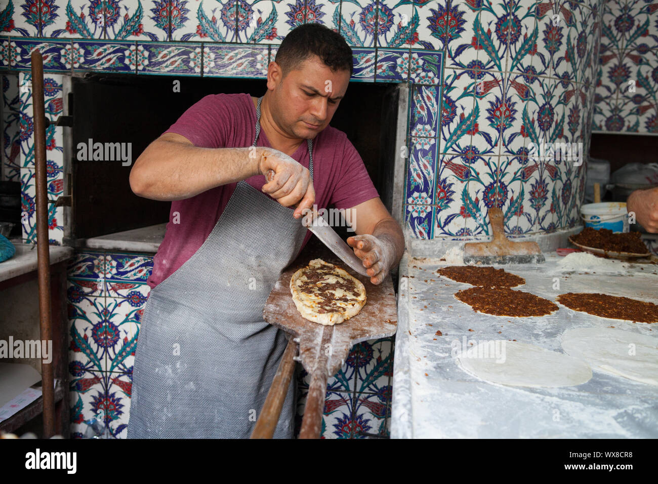 A restaurant worker using a knife to prepare pide (Turkish pizza) in a restaurant in Istanbul Stock Photo