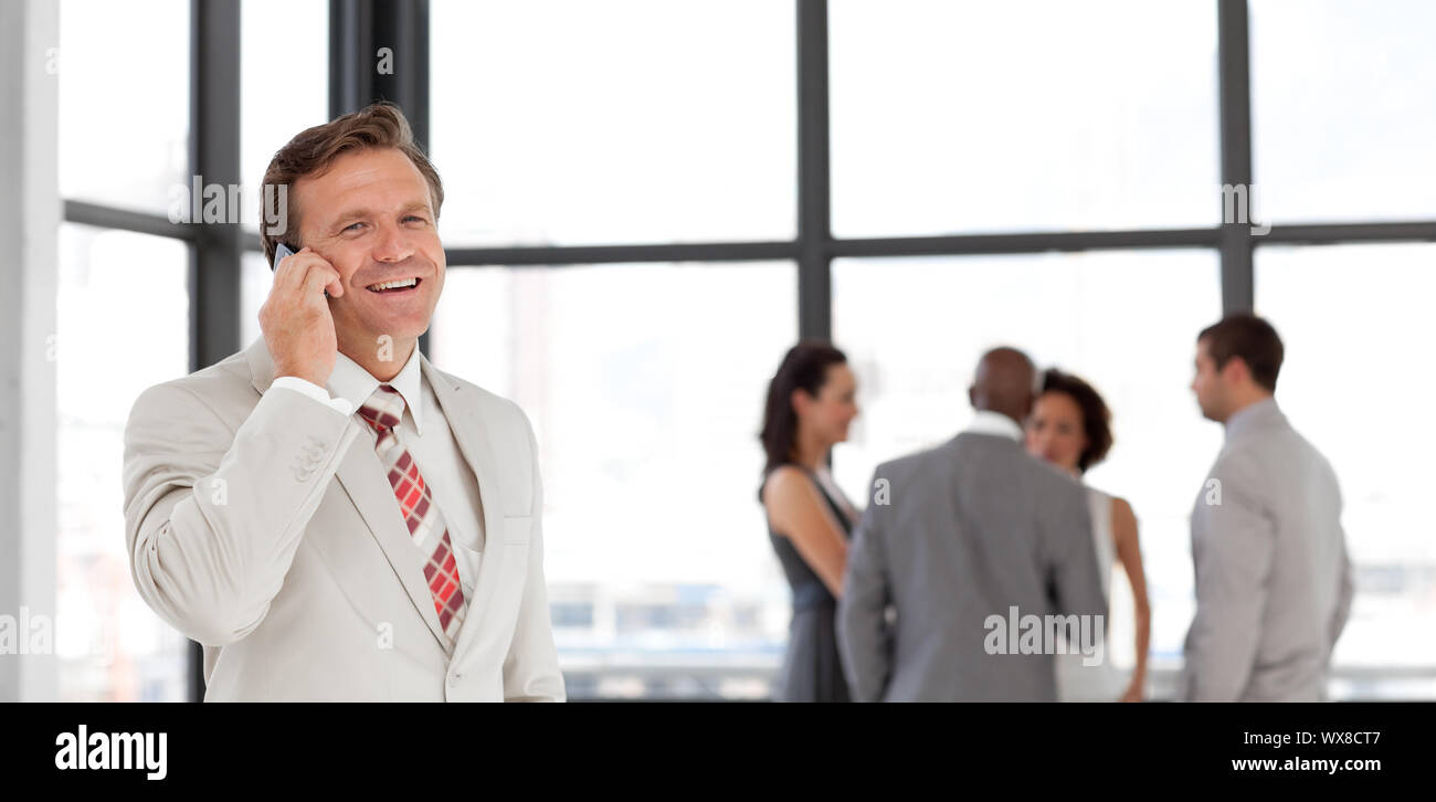Portrait of a smiling businessman on phone with his team Stock Photo