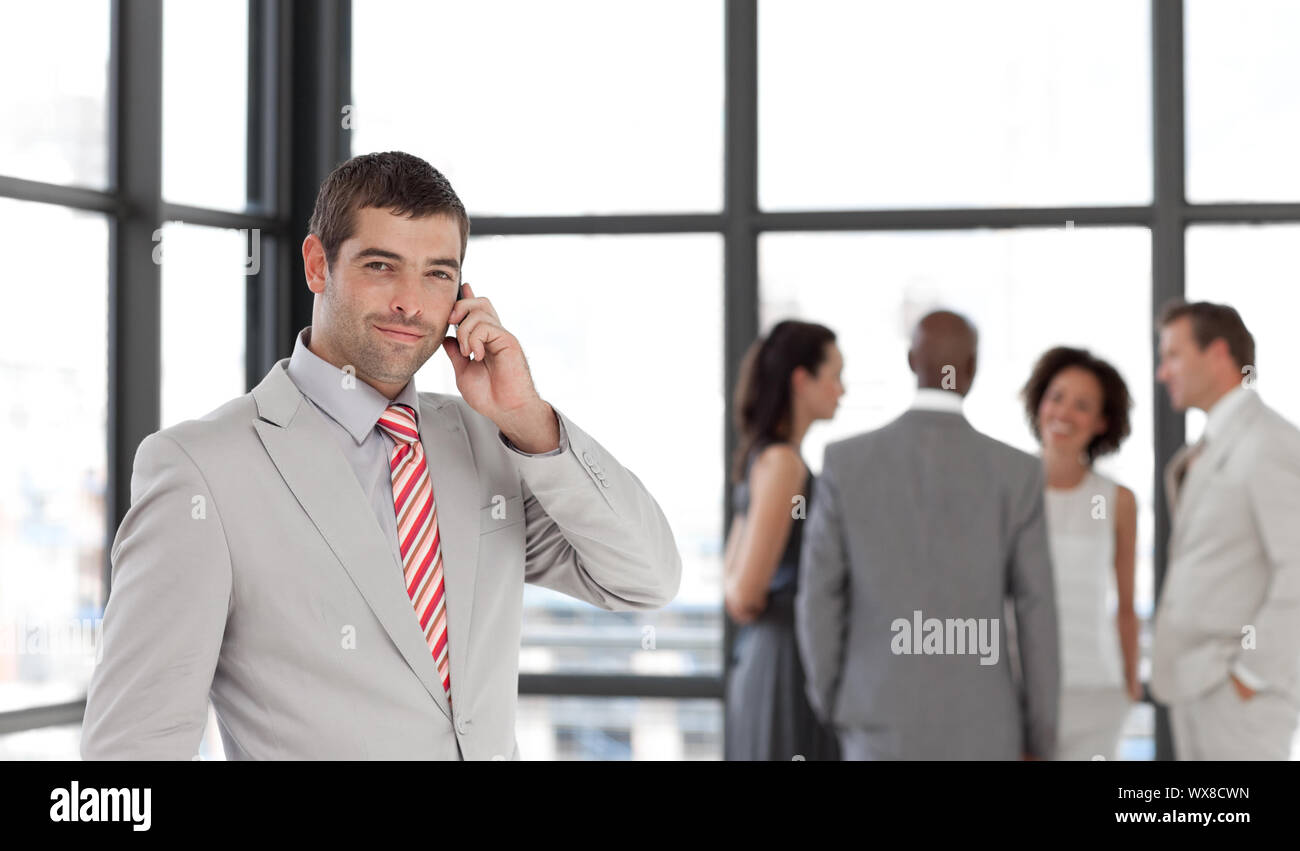 Cute businessman on phone in office with his team Stock Photo