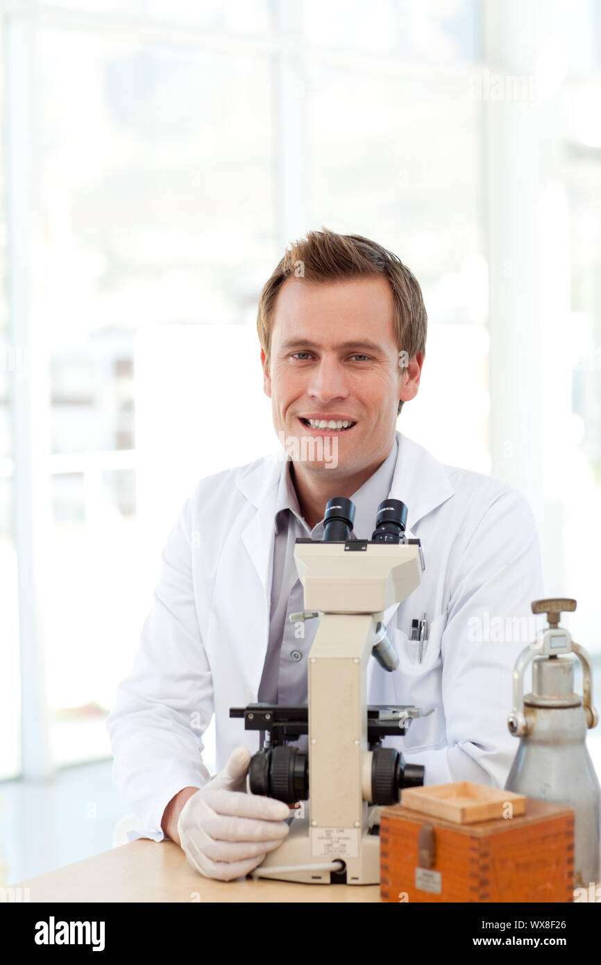 Male scientist looking at a slide under a microscope in a laboratory
