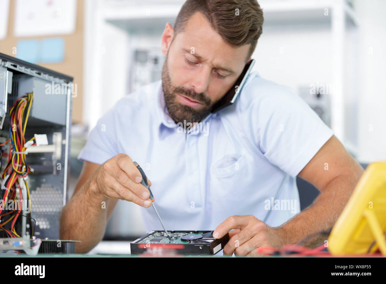 male worker calling customer while disassembling a pc Stock Photo - Alamy