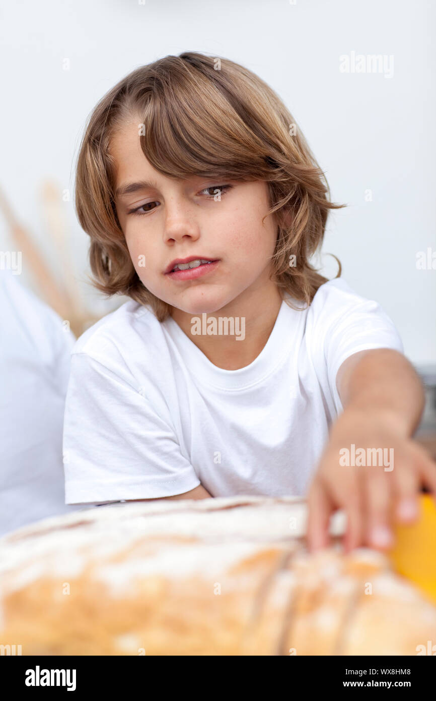 Little boy eating bread in the kitchen Stock Photo