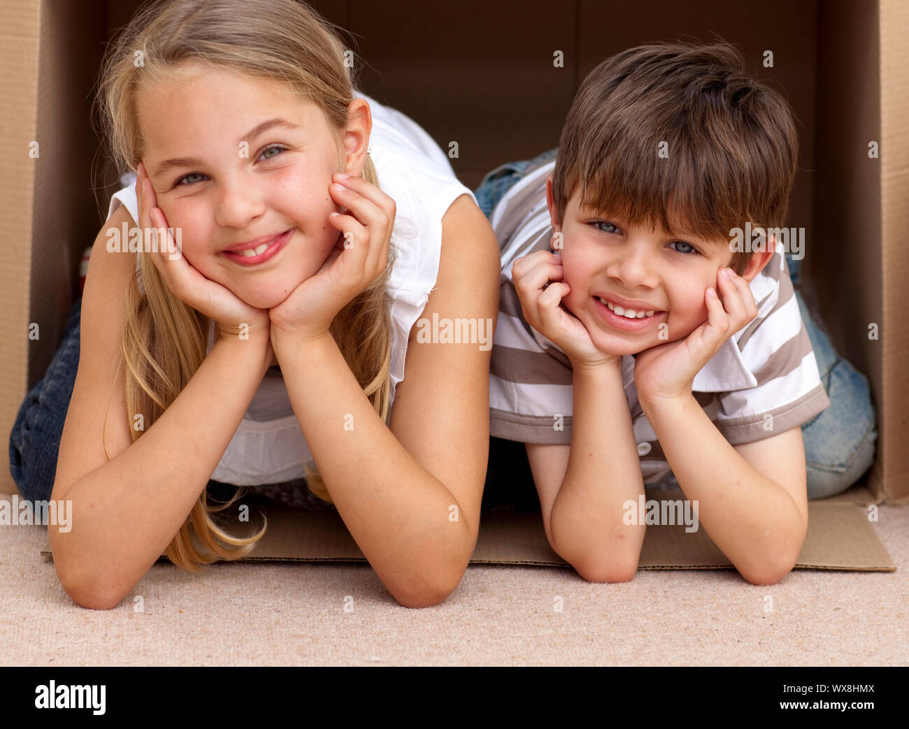 Smiling siblings playing with boxes after moving house Stock Photo Alamy
