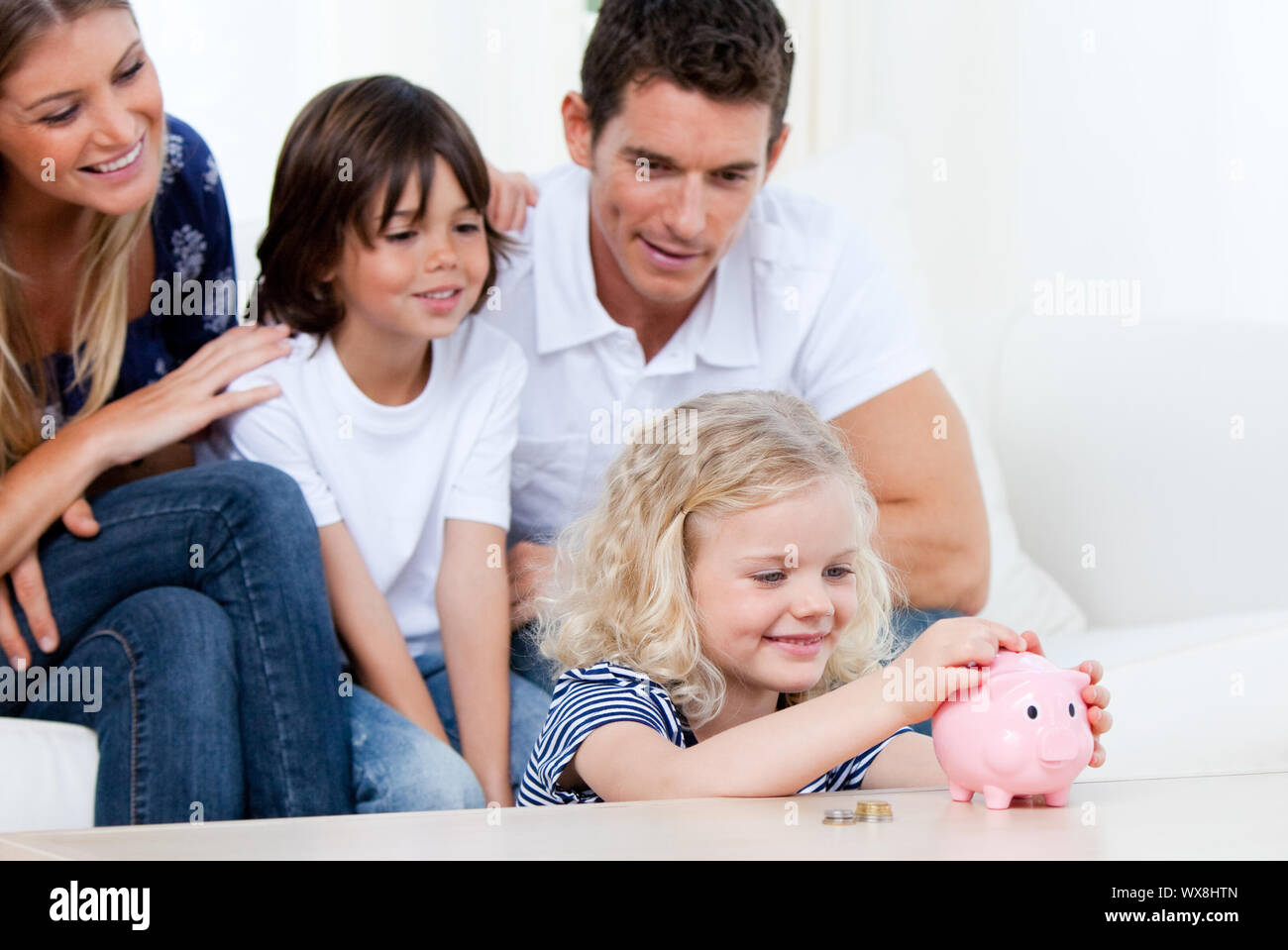 Positive family using a piggy bank at home Stock Photo - Alamy