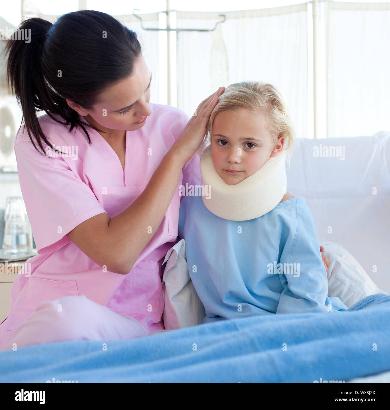 A nurse looking after an upset girl with a neck brace in a hospital