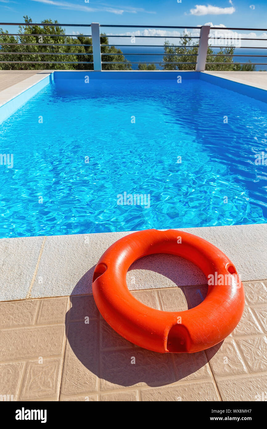 Orange life buoy lying at swimming pool Stock Photo