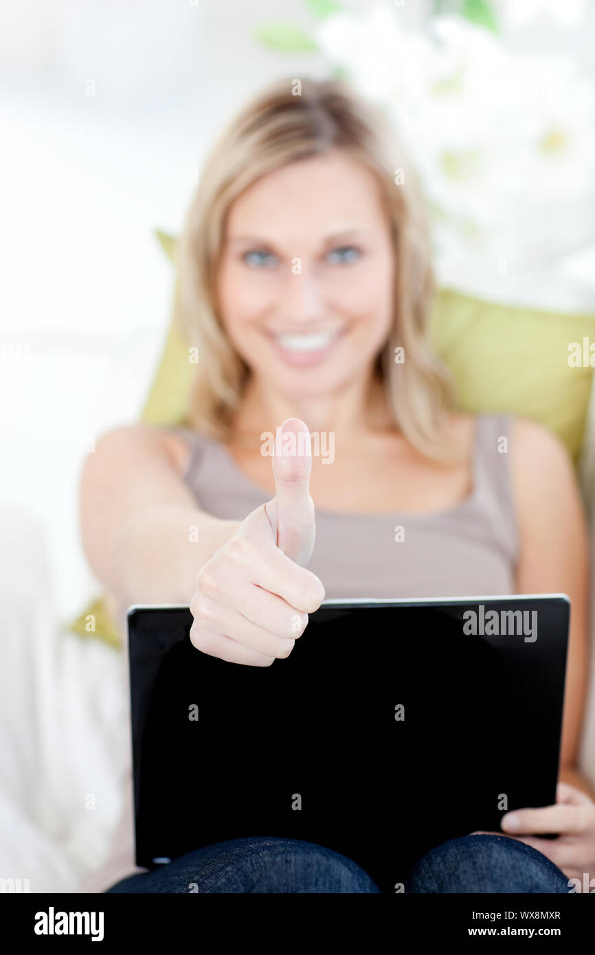 Smiling woman with a laptop holding her thumb up Stock Photo - Alamy