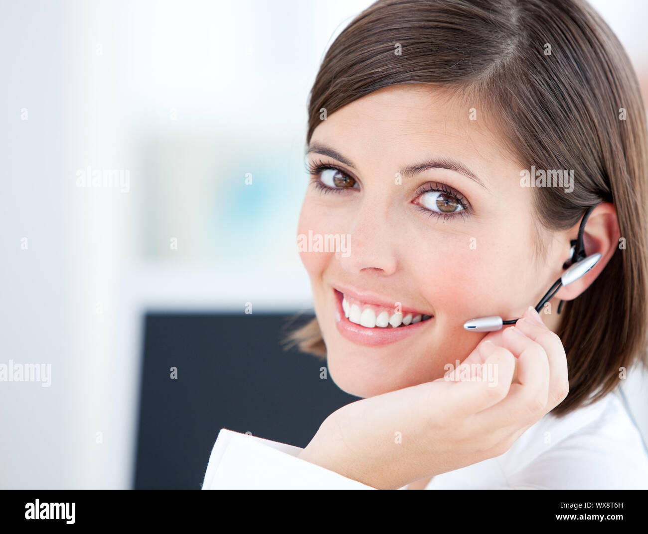 Cute businesswoman talking with clients in front of her computer in the office Stock Photo