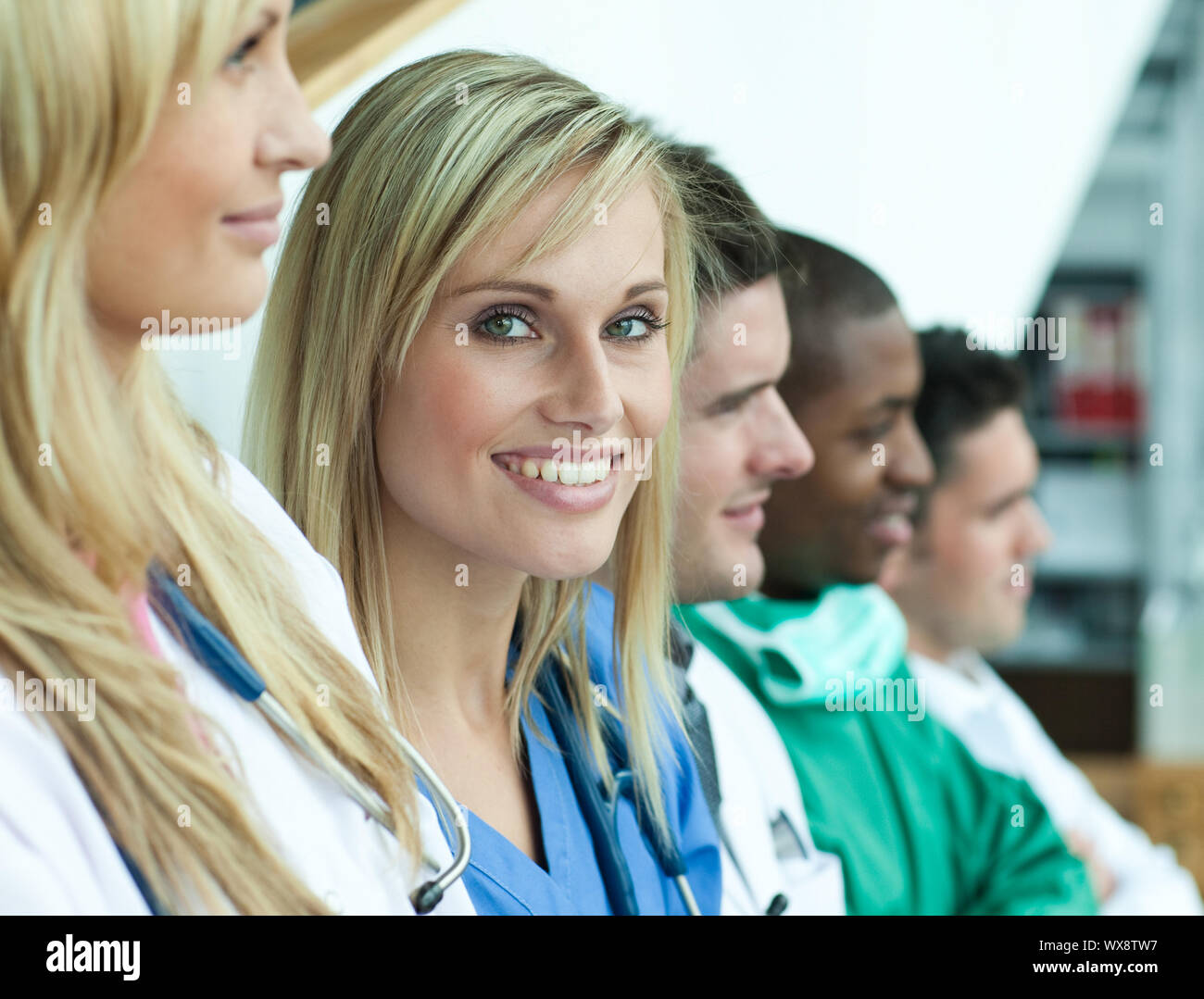 Portrait of female doctor smiling at the camera with her team in a line on stairs Stock Photo