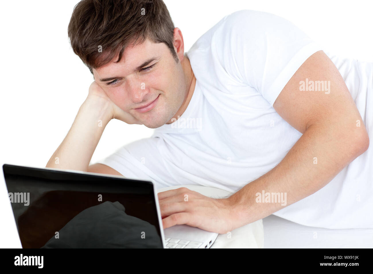 smart man working on his computer lying on the floor against a white ...