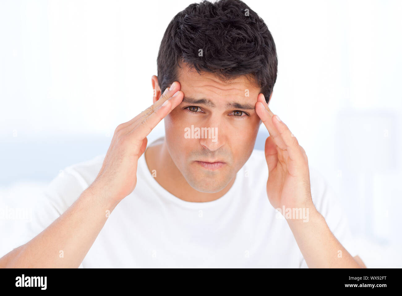 Exhausted man suffering from a headache in his bedroom Stock Photo Alamy