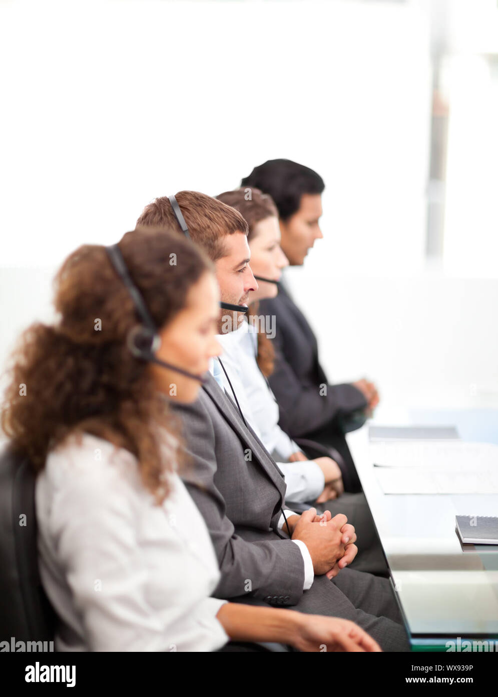 Four businesspeople on the phone sitting at their desk  in a row Stock Photo