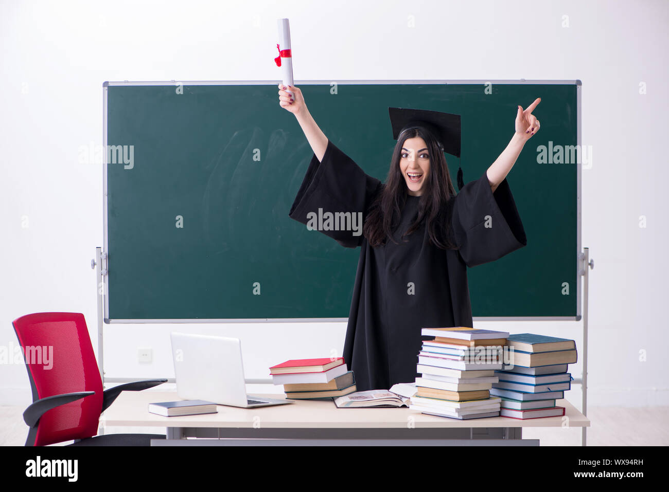 Female graduate student in front of green board Stock Photo - Alamy