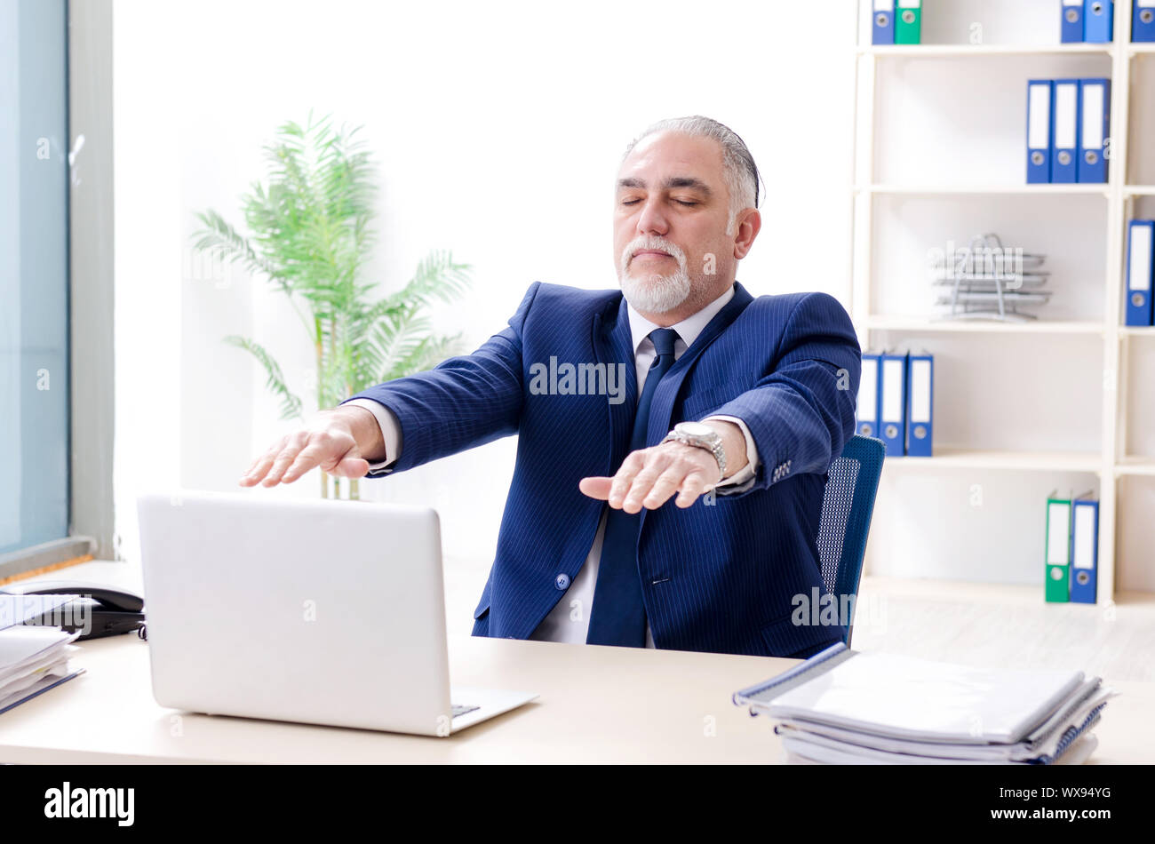 Aged businessman doing yoga exercises in the office Stock Photo - Alamy