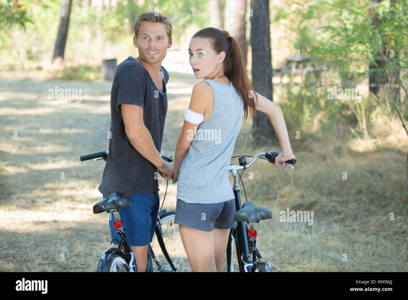 couple with bicycles looking over shoulders in surprise Stock Photo