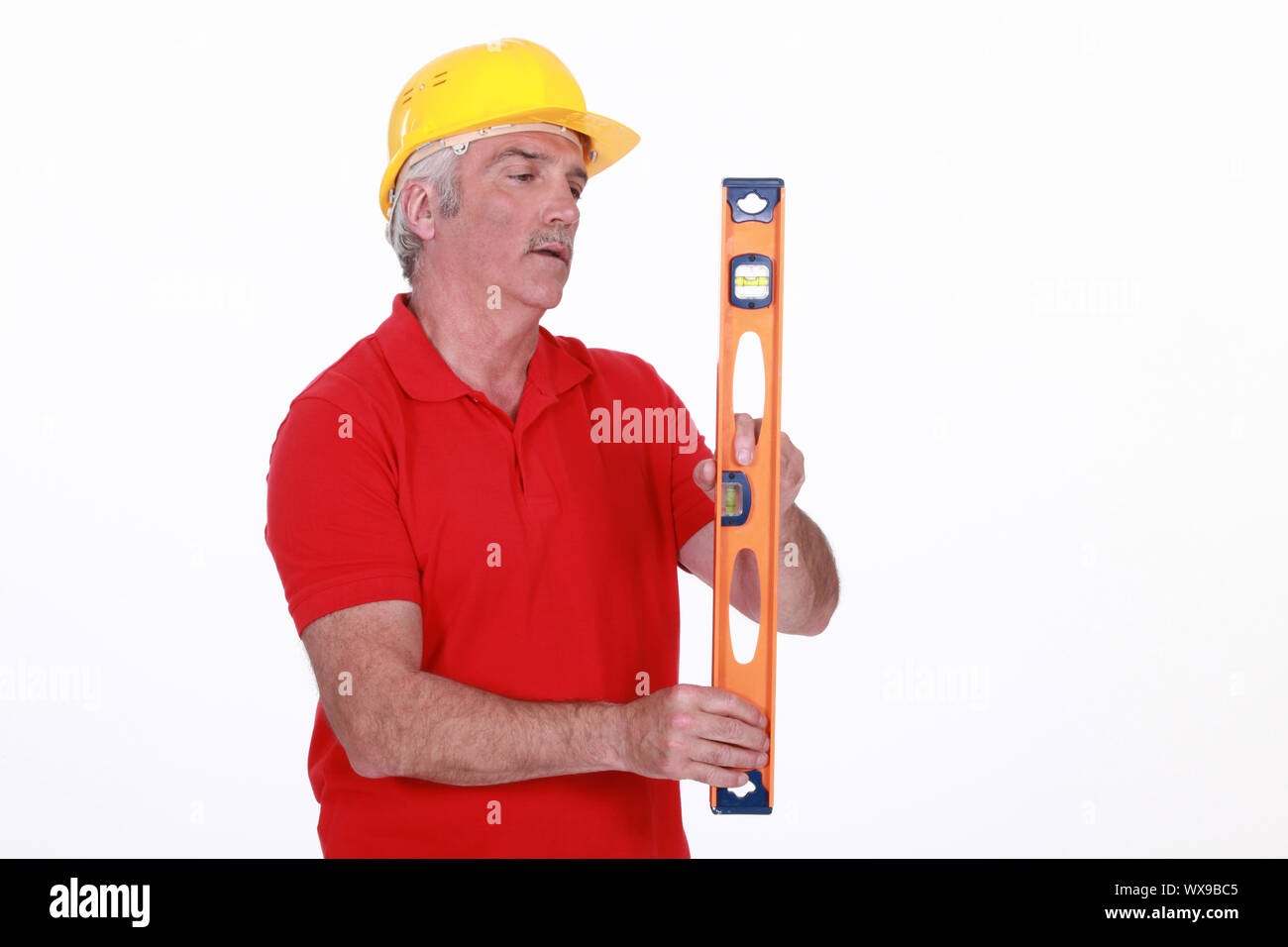 Grey-haired man holding spirit-level Stock Photo