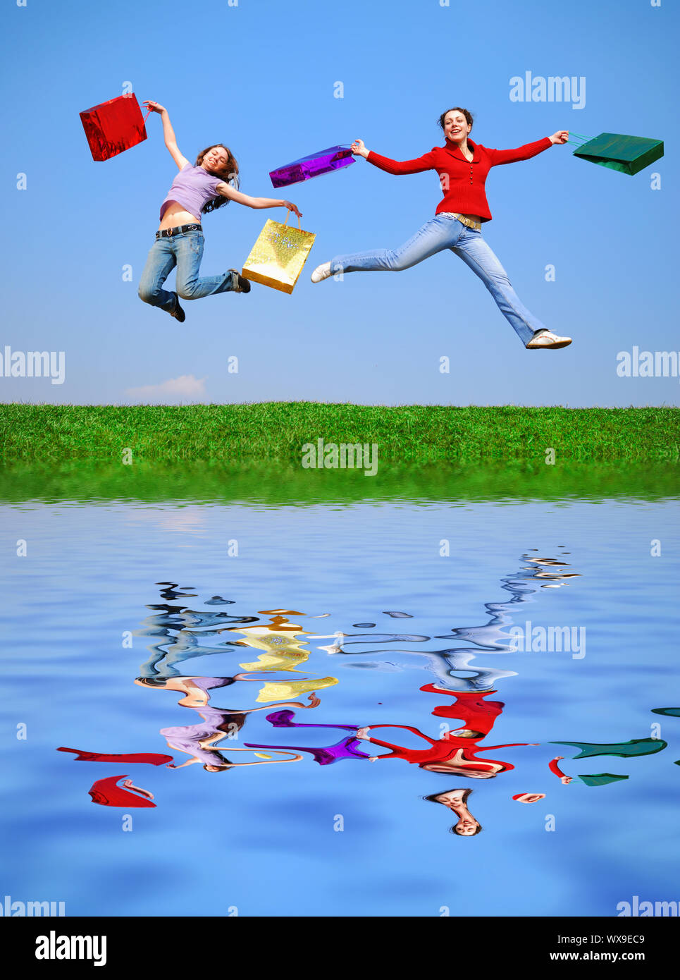 Girls jumping with bags against blue sky with reflection on water Stock ...