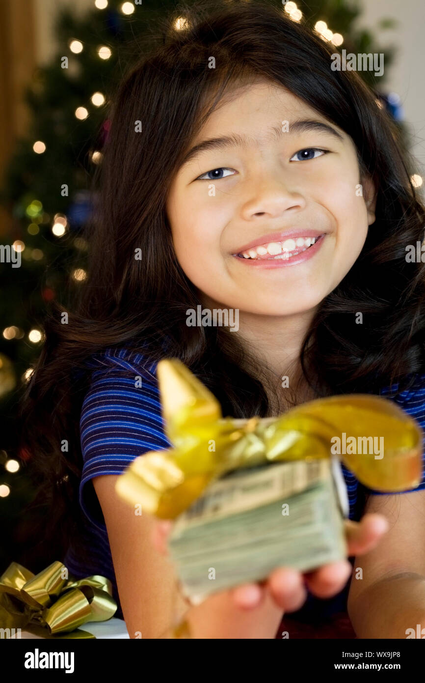 Little girl holding large amount of cash with Christmas tree in ...