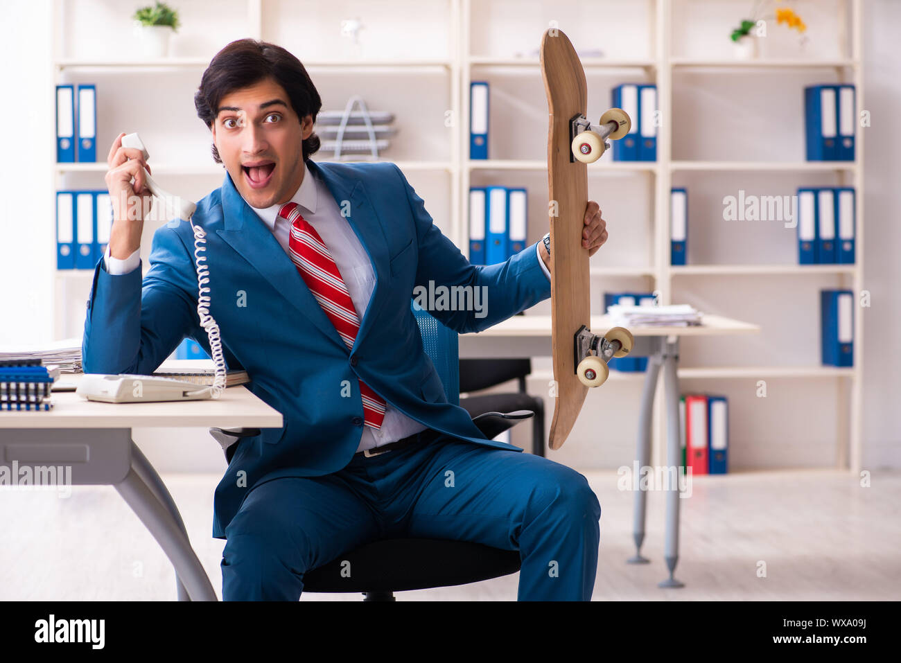 Young handsome businessman with longboard in the office Stock Photo - Alamy