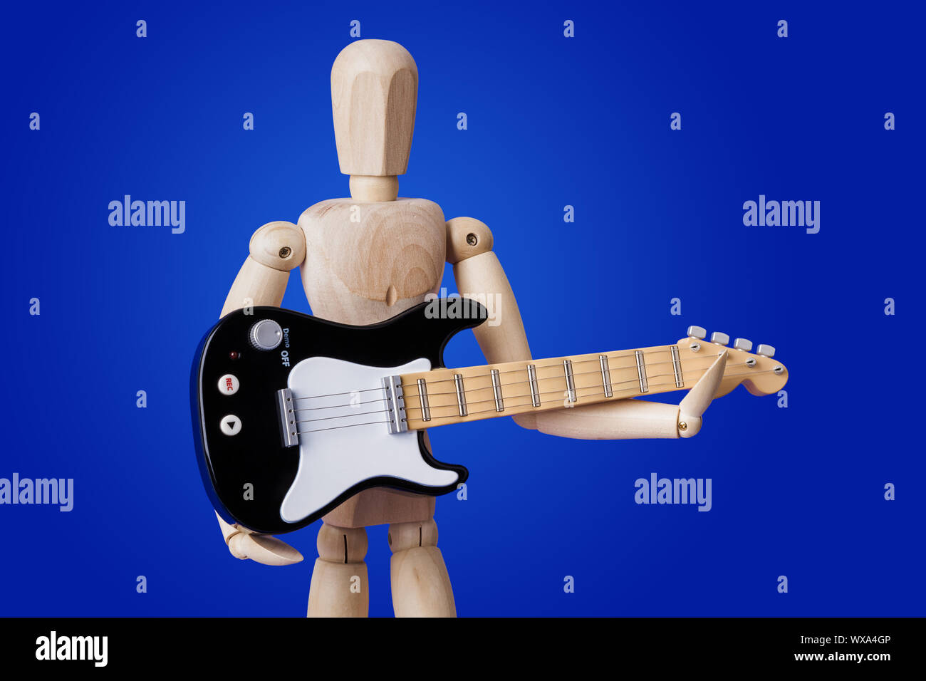 Wooden toy figure with electric guitar on blue Stock Photo
