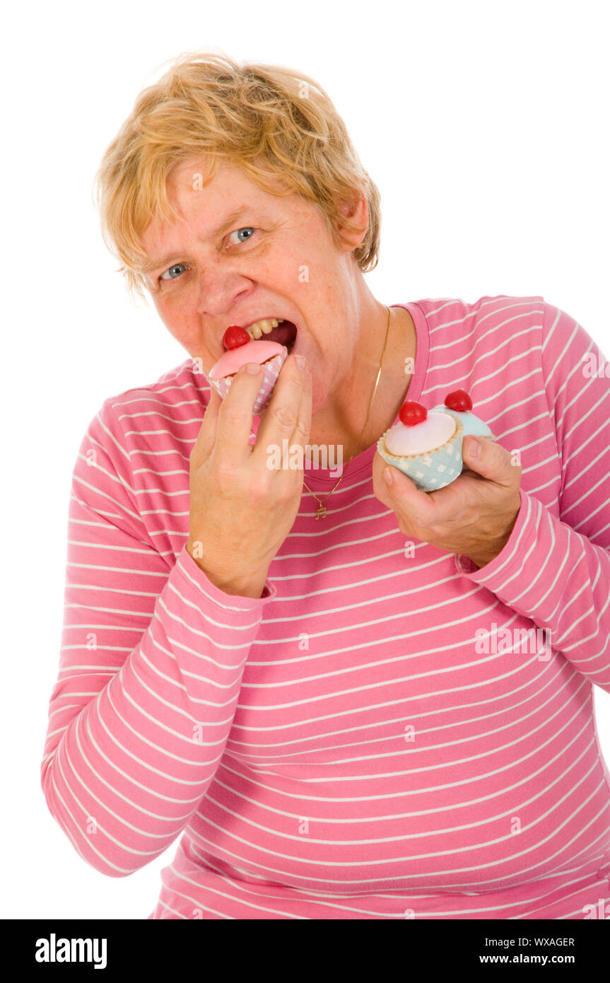 Elderly woman is eating fancy cakes Stock Photo