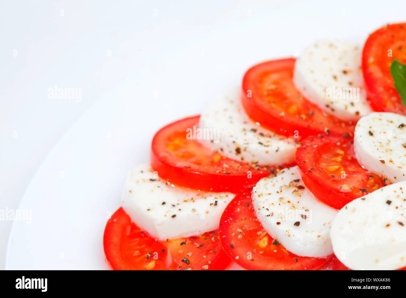 Tomato and mozzarella with basil leaves on a plate Stock Photo - Alamy