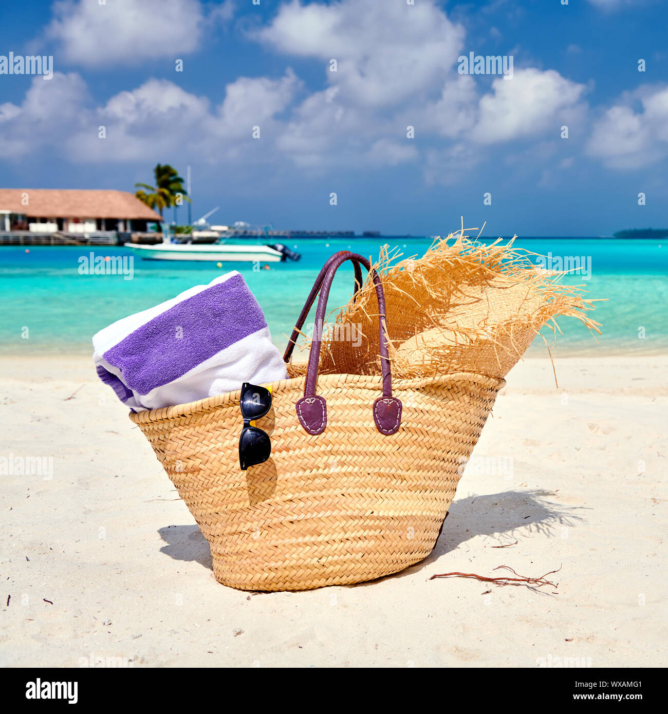 Straw bag with hat and towel on beach Stock Photo - Alamy