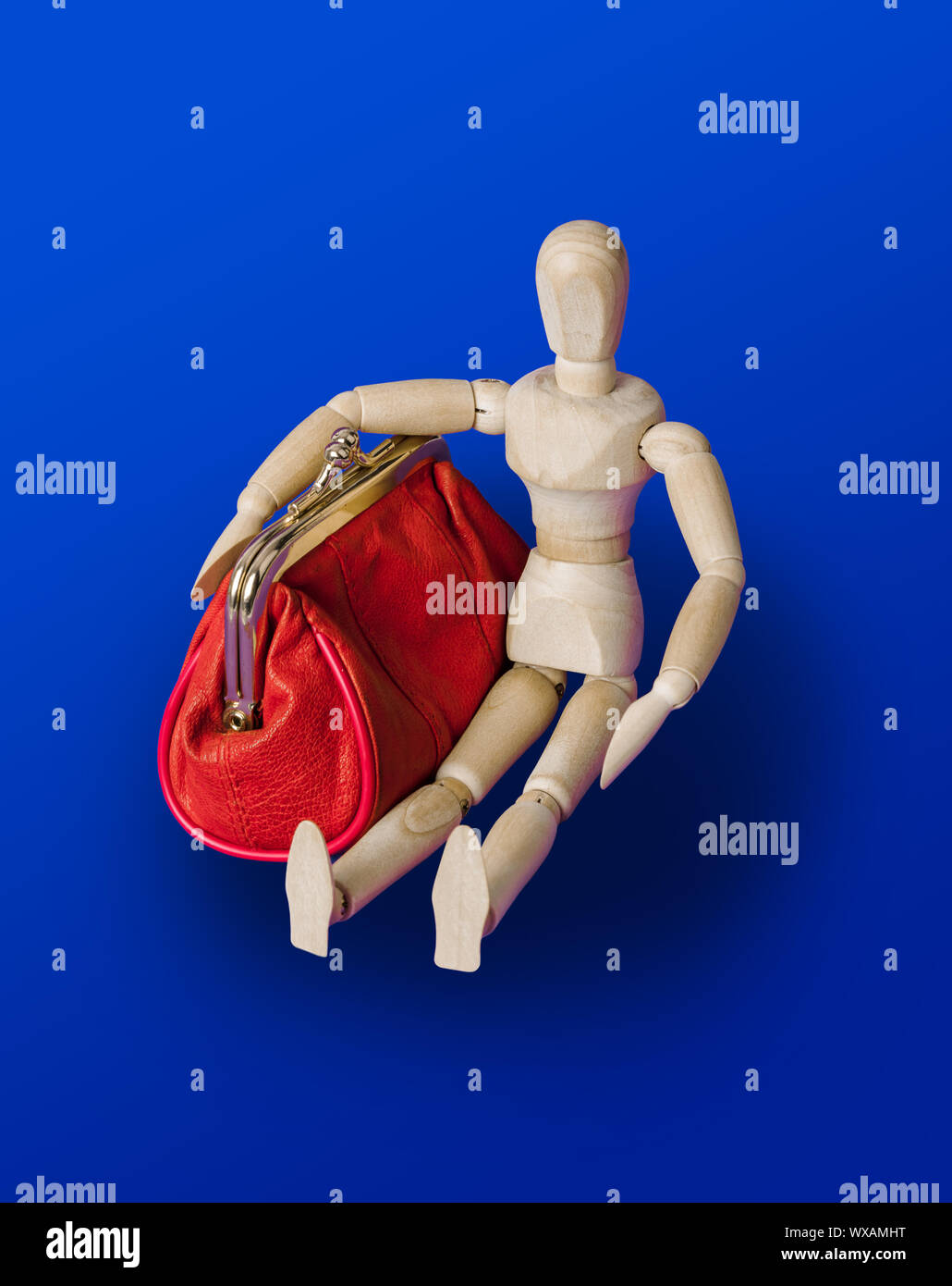 Wooden toy figure with red purse on blue Stock Photo