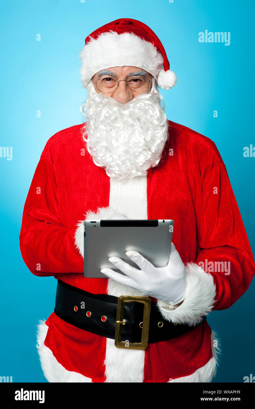 Modern Santa using digital touch screen device. Facing camera and ...