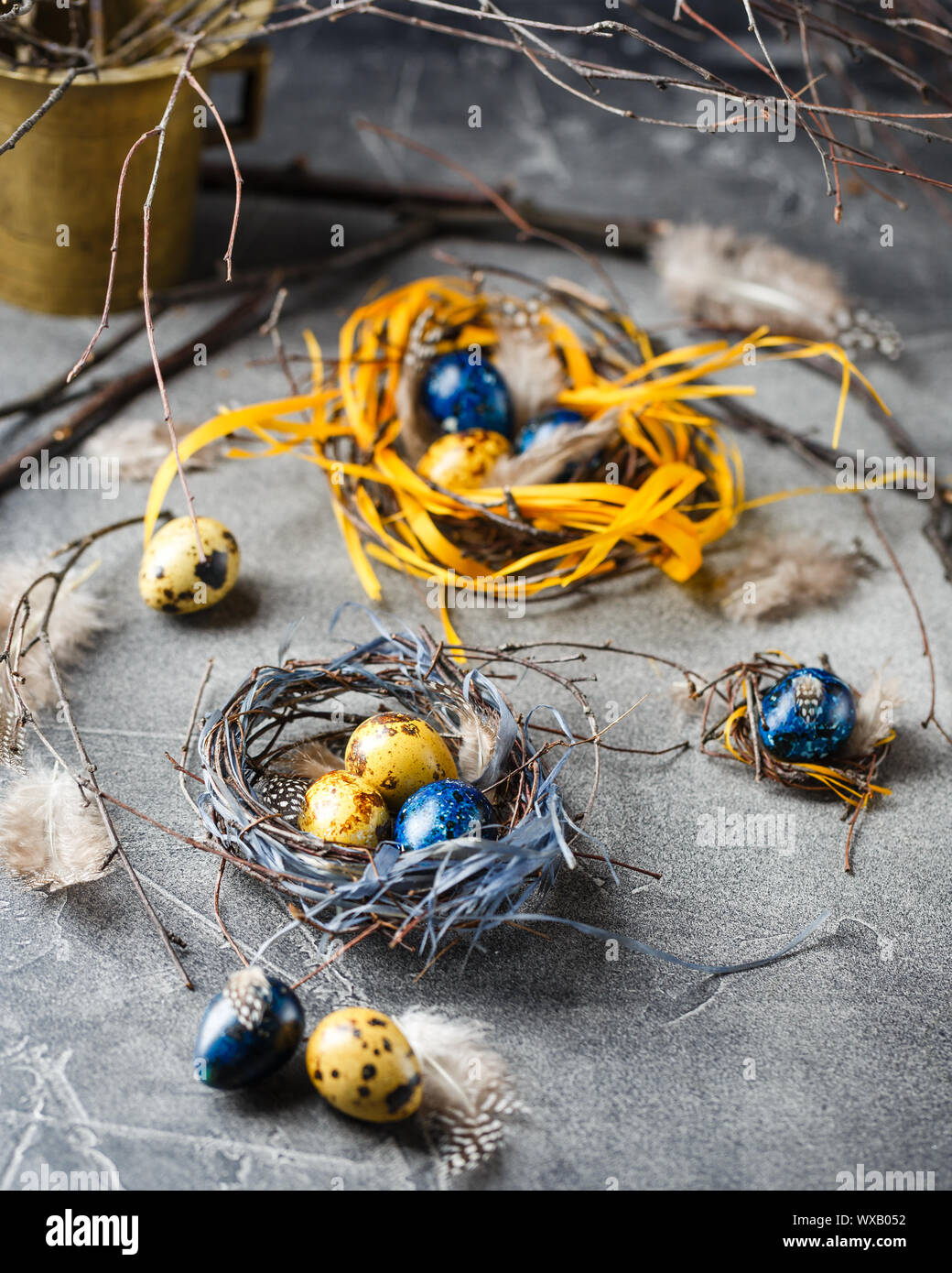 Quail easter eggs with feathers in nest on brown table with copy space