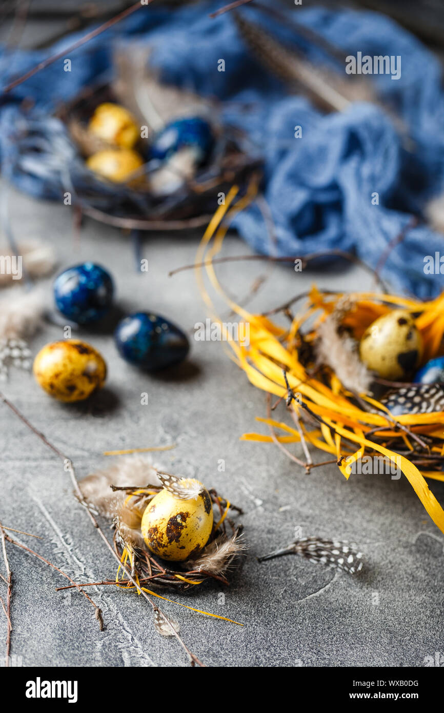 Quail easter eggs with feathers in nest on brown table with copy space
