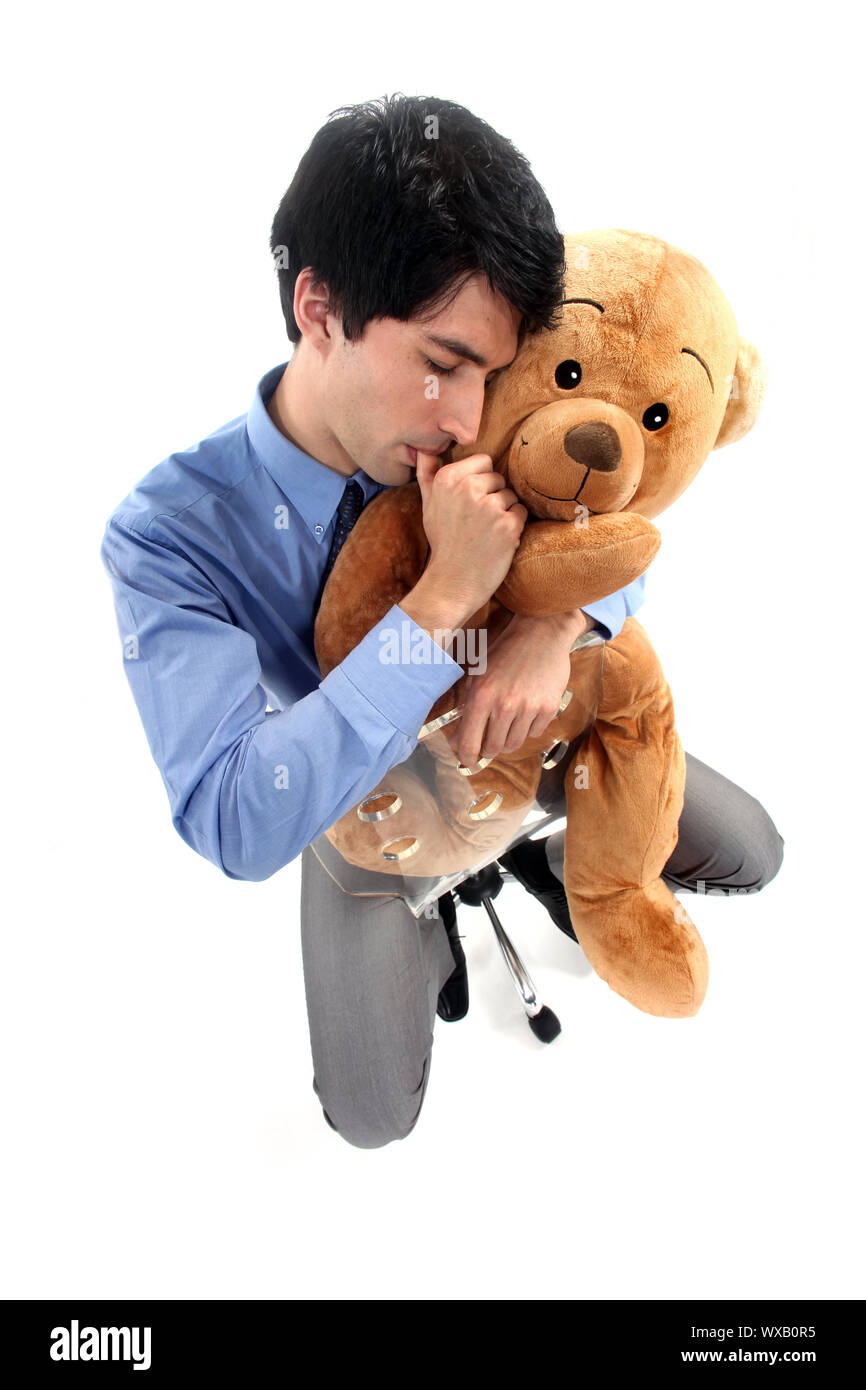 Businessman hugging teddy bear and sucking thumb Stock Photo