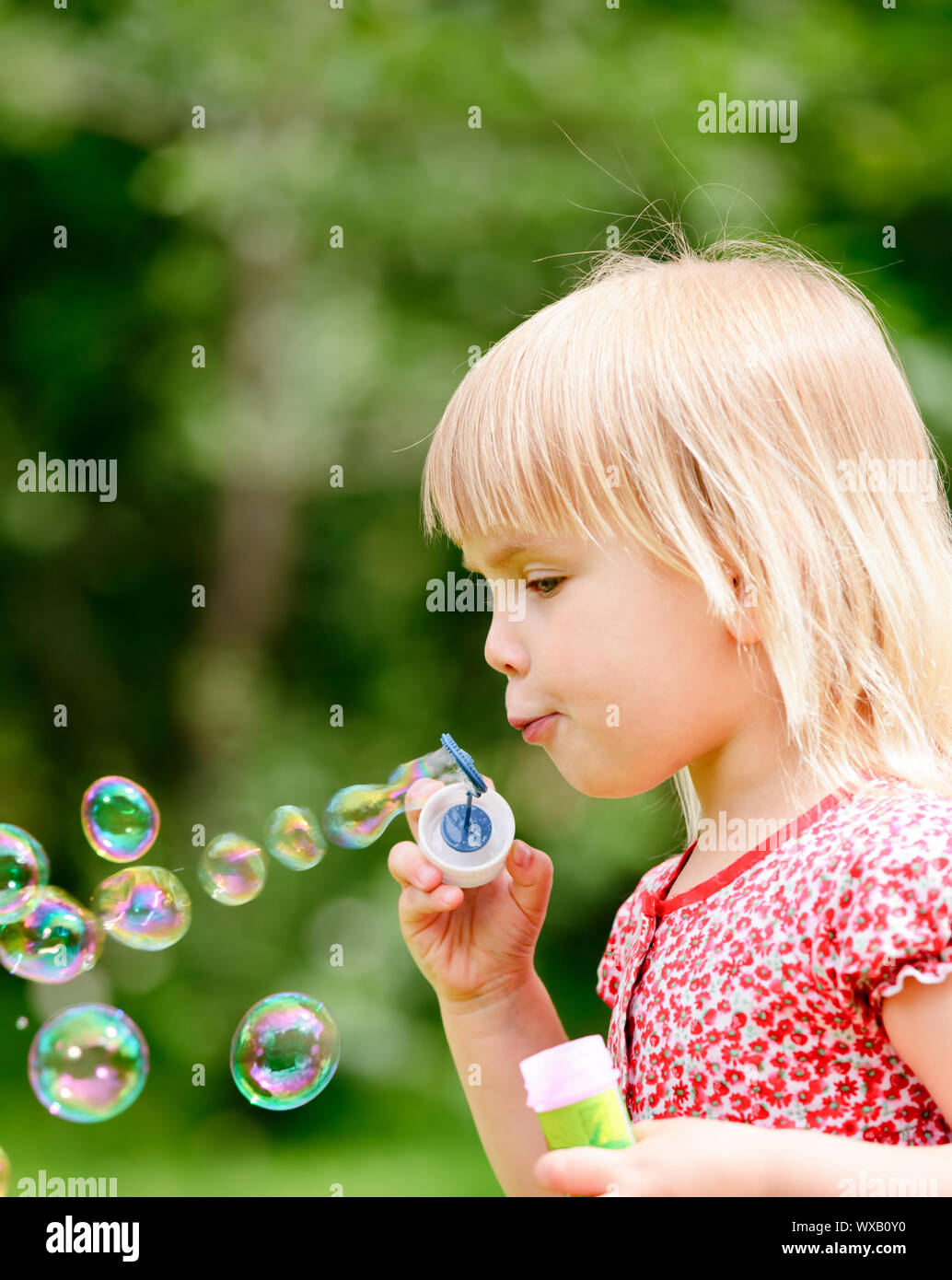 Cute little girl making soap bubbles outdoors Stock Photo - Alamy