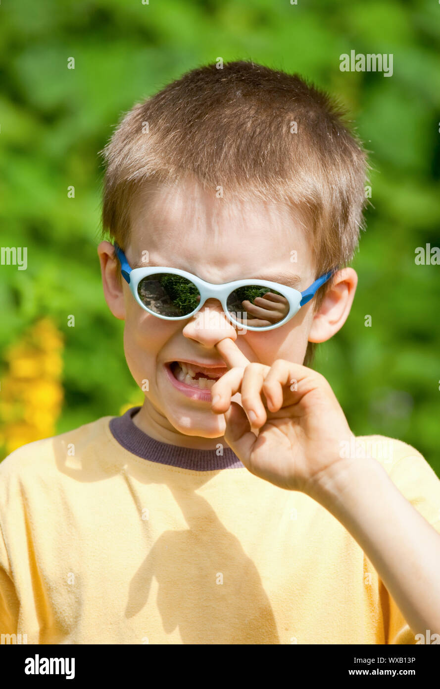 Portrait of a young boy wearing sunglasses picking his nose Stock Photo