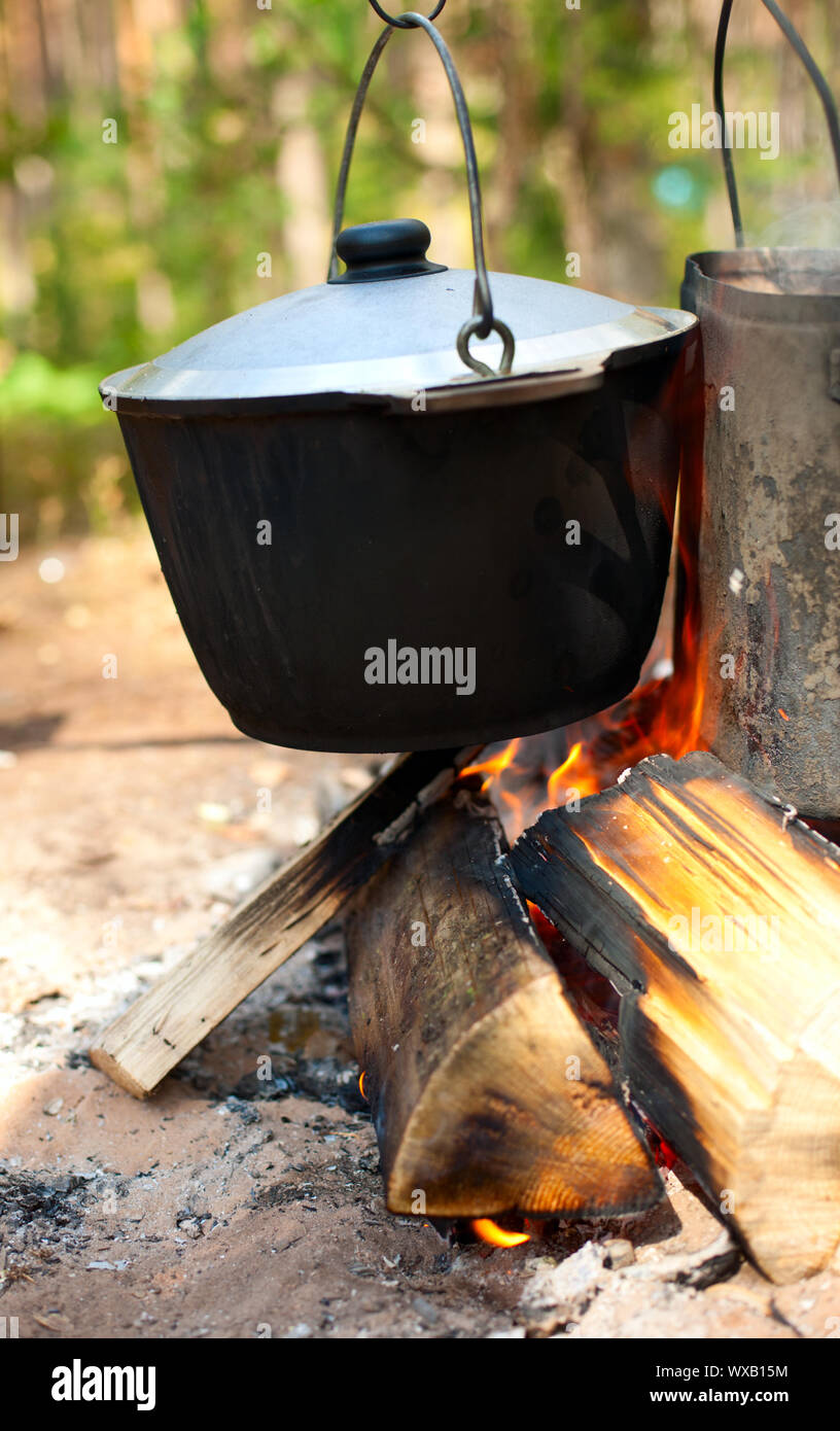 Camping kettles over burning campfire Stock Photo - Alamy