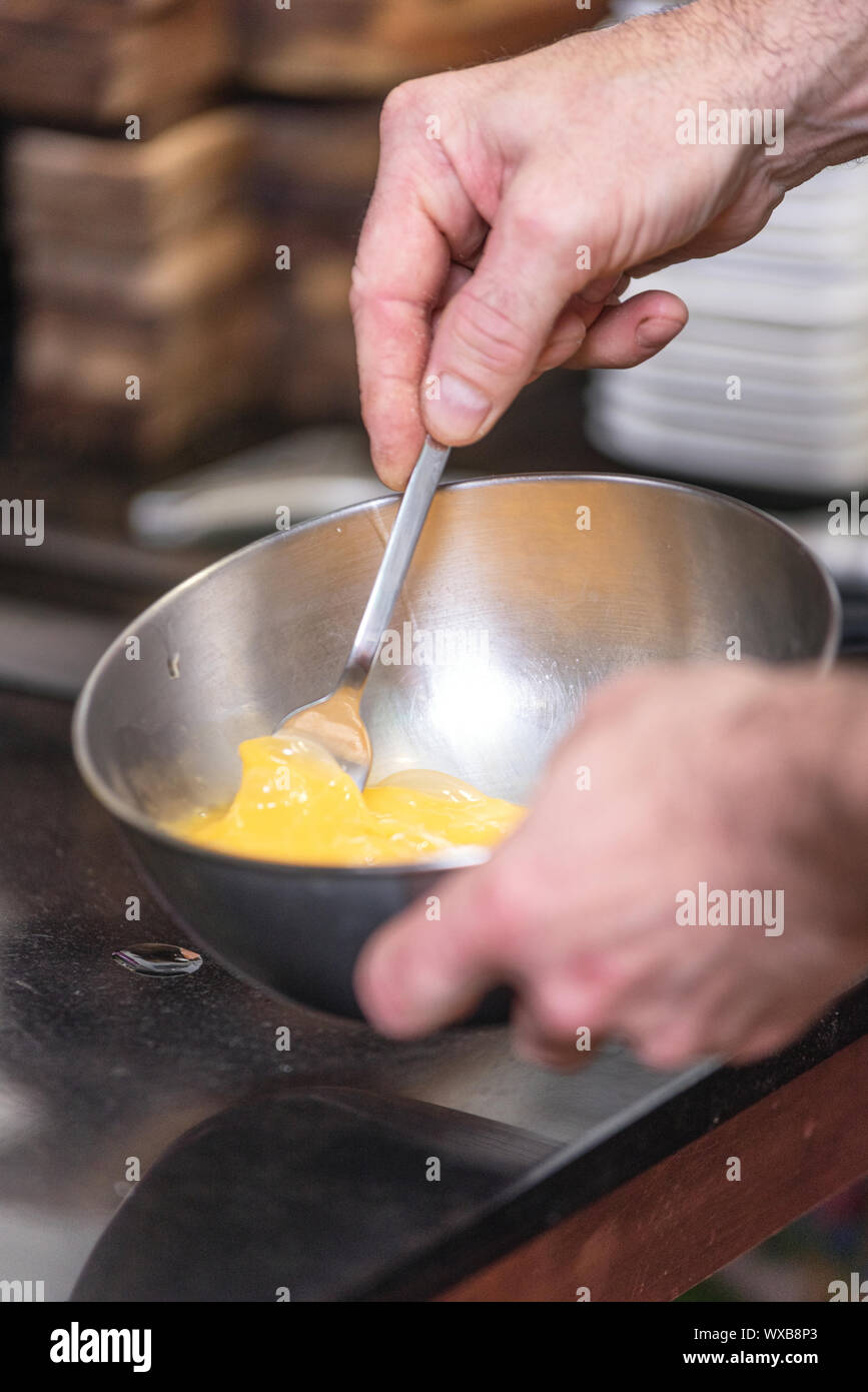 Chef hands beating eggs in a bowl . Stock Photo