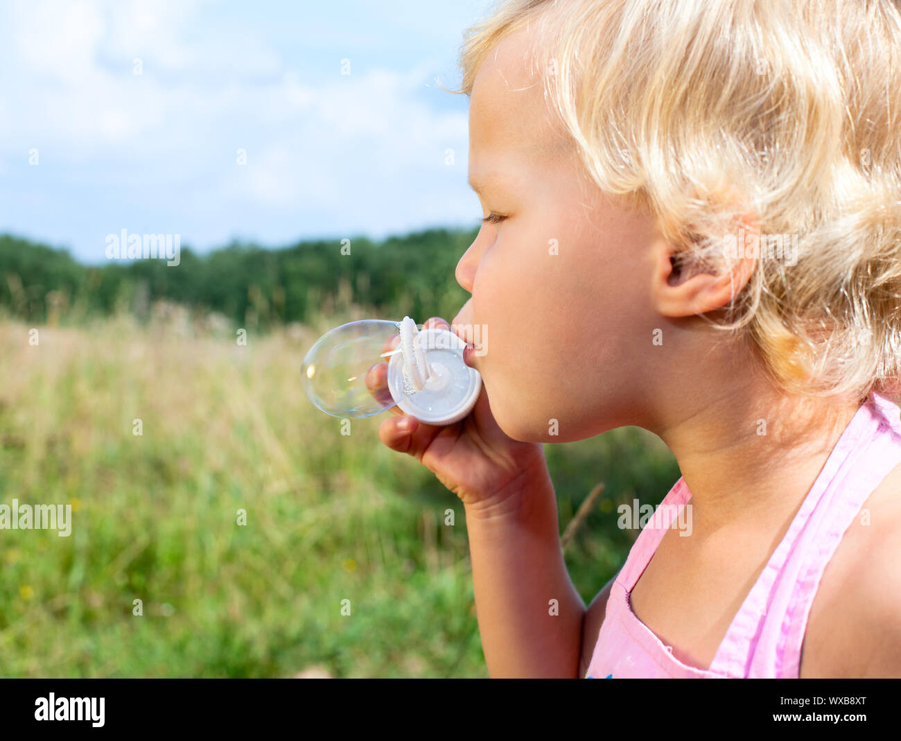 Cute little girl making soap bubbles outdoors Stock Photo - Alamy