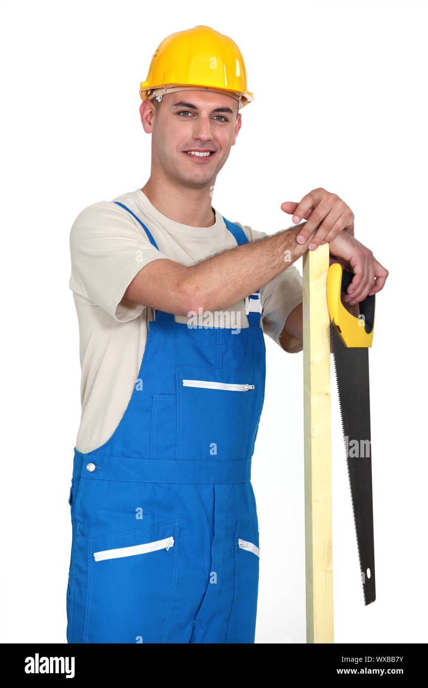 Happy tradesman holding a plank of wood and a saw Stock Photo